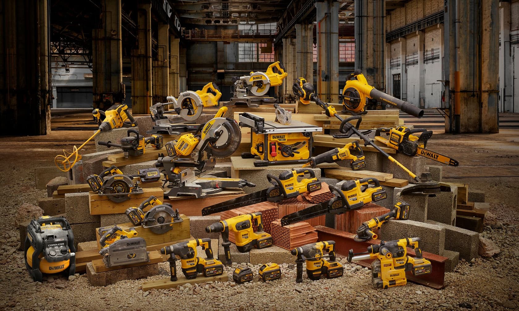 A group of various DEWALT power tools, including drills, saws, grinders, and blowers, arranged on construction materials inside an industrial building.